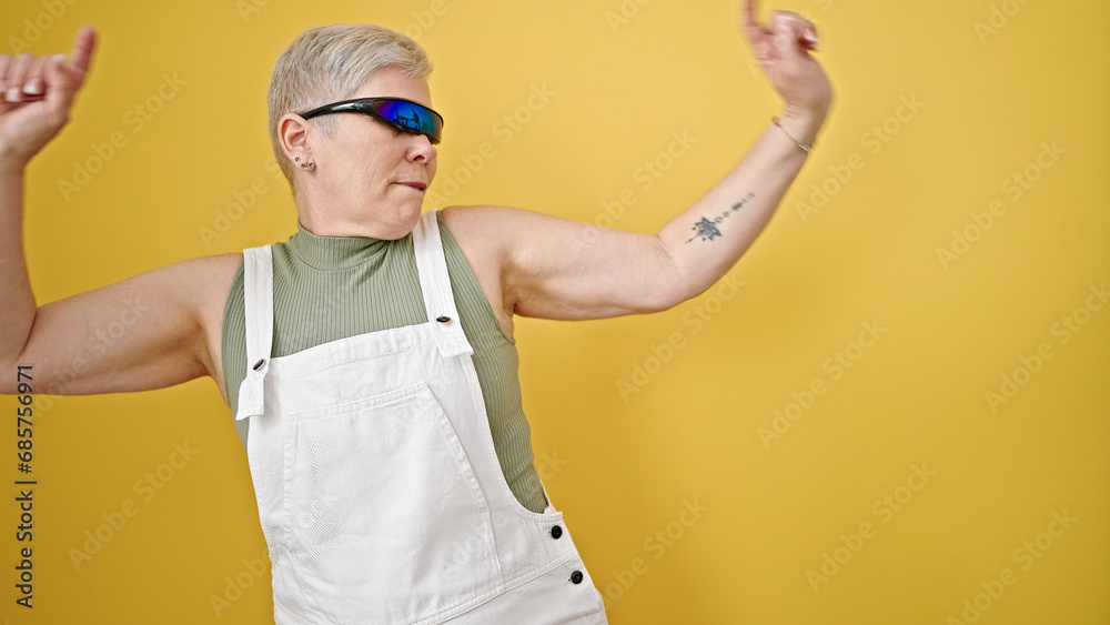 Sticker Middle age grey-haired woman using virtual reality glasses dancing over isolated yellow background