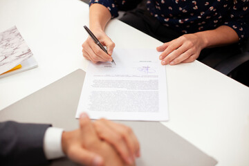 High angle view close up of adult woman signing a contract during meeting