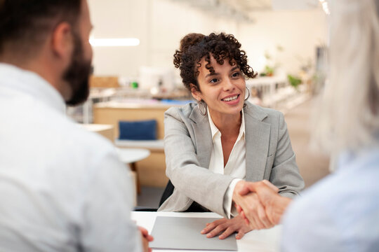 Female bank worker shaking hands with clients after meeting