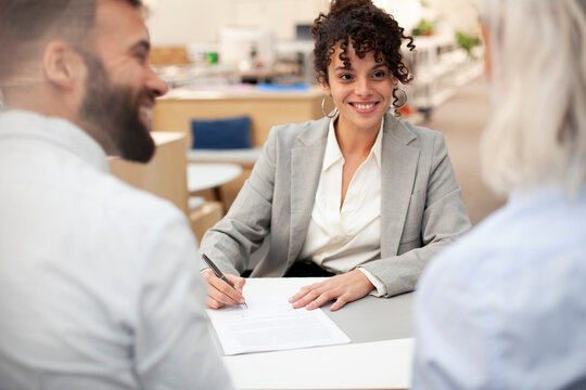 Bank worker signing contract while talking with clients