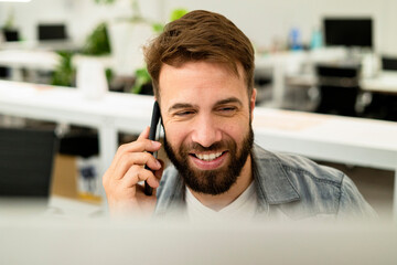 Male system engineer listening to voice mail while using computer
