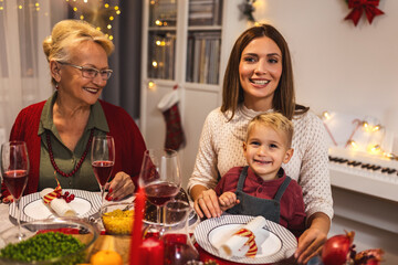 Happy family having Vhristmas dinner with their grandparents. Eating homemade food, drinking beverages. Home is decorated for New Year's Eve and Christmas