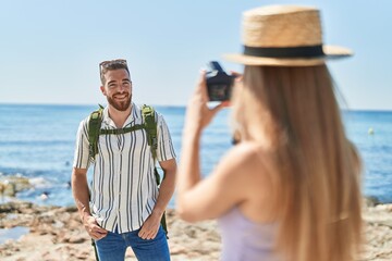 Man and woman tourist couple smiling confident make photo by professional camera at seaside