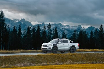 Pickup truck running on the beautiful road along the mountains and forest. Front side view of a...