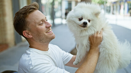 Cheerful young caucasian man confidently smiling while sitting with his joyful puppy on a city bench, enjoying the positive outdoors expression of urban happiness.