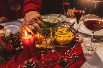 Lighting a candle on the dining table. Family having Christmas dinner.