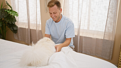 Happy young caucasian man confidently playing with his dog on a relaxing morning in his comfortable...