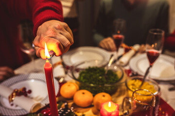 Fototapeta na wymiar Lighting a candle on the dining table. Family having Christmas dinner.