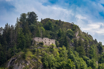 Fototapeta na wymiar The ruins of the Vršatec castle standing on a high rock. The castle is surrounded by trees.