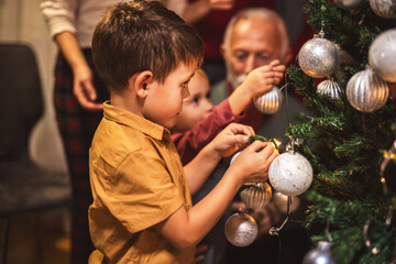 Family decorating together a tree with lights and balls. Christmas time.