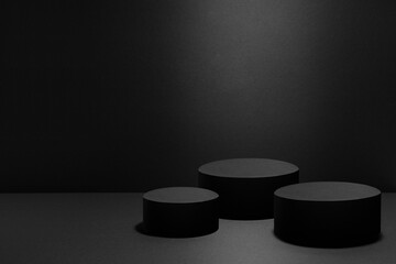 Abstract three black round podiums for cosmetic products with light beams, mockup on black background. Scene for presentation products, goods, advertising, design, display, showing in concert style.