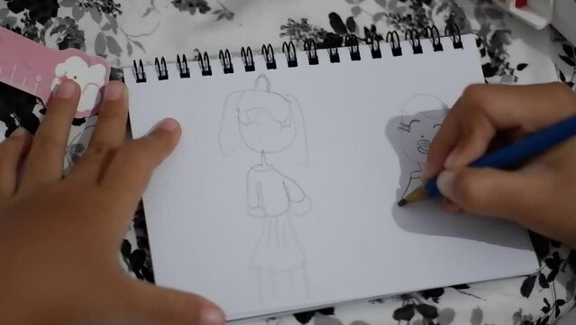 Hands little girl drawing on white paper with pencil.