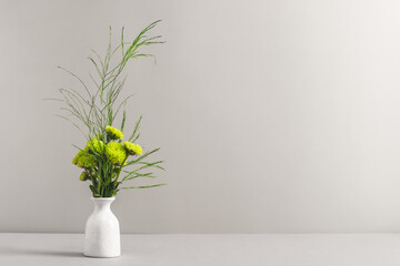 A bouquet of small green chrysanthemums in a ceramic mini vase on a white table. Women's workplace,...