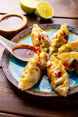 Asian dumplings with hot sauce on the dark wooden background close up vertical photo