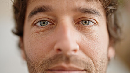 Young hispanic man standing with serious expression at home