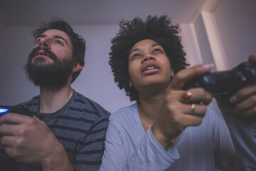 Young multiethnic couple bedroom playing videogame  v