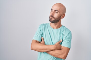 Middle age bald man standing over white background looking to the side with arms crossed convinced and confident