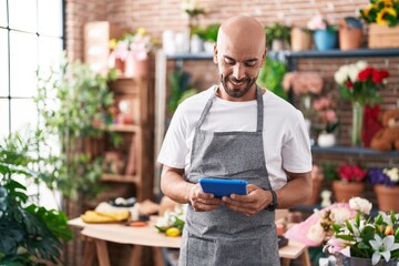 Young bald man florist smiling confident using touchpad at florist