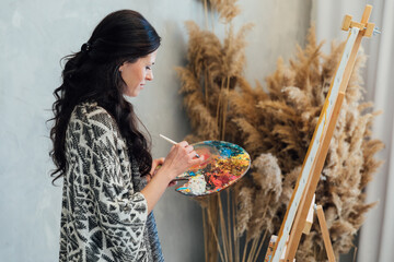 Woman artist painting with paints beautiful picture