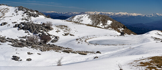Fototapeta na wymiar Panoramic winter landscape with frozen lake at Mount Avgerinos in Epirus, Greece