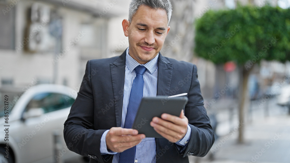 Canvas Prints Young hispanic man business worker smiling confident using touchpad at street