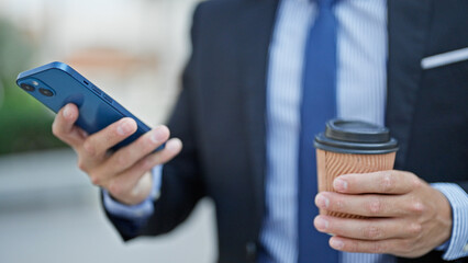 Young hispanic man business worker using smartphone drinking coffee at street
