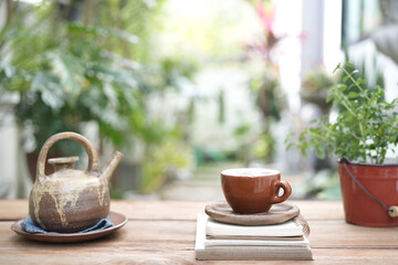 Antique kettle Traditional Earthenware teapot and tea cup and notebooks on wooden table