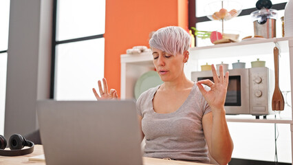 Young woman using laptop doing yoga exercise at dinning room
