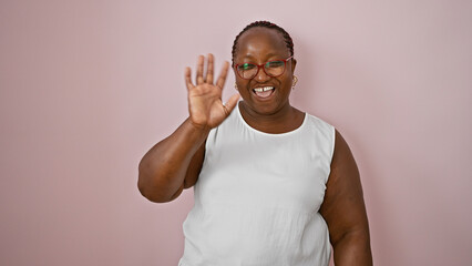 Confident african american woman joyfully saying hello, smiling over isolated pink background, hand...