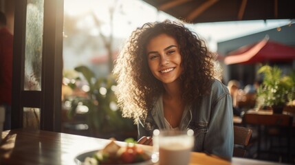 Young woman smiling while sitting outside at a table on a restaurant patio and eating delicious. Street food concept.