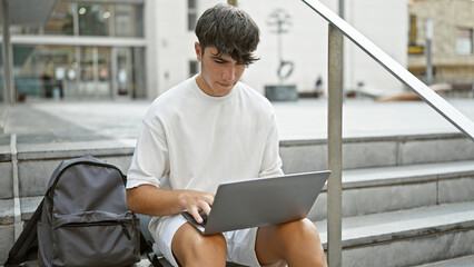 Cool young hispanic teenager, a smart university student engrossed in online study on laptop while...