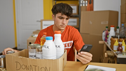 Dedicated young hispanic teenager volunteer working with passion, thoroughly checking food products...