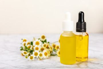 Glass bottle with chamomile essential oil on an old wooden background. Chamomile flowers, close up. Aromatherapy, spa and herbal medicine ingredients. Beauty concept.Copy space. Natural cosmetic