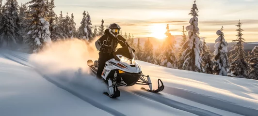 Fotobehang Snowmobiler racing through snowy landscape at sunset © thodonal