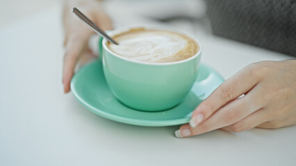 Young blonde woman holding cup of coffee at coffee shop terrace