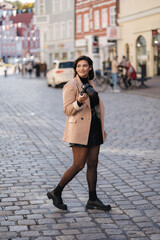 Fototapeta premium Beautiful woman photographer walking in the city with mirrorless camera. Life style concept
