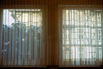 Innenausstattung von Raum mit weißen durchsichtigen Gardinen vor Doppelfenster und Ausblick auf...