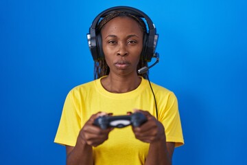 African american woman playing video games skeptic and nervous, frowning upset because of problem. negative person.