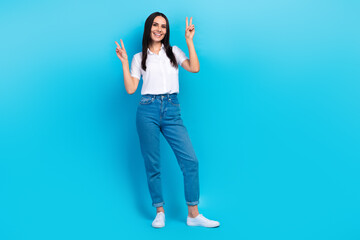 Fototapeta premium Full length photo of pretty sweet girl dressed white shirt walking showing two v-signs empty space isolated blue color background