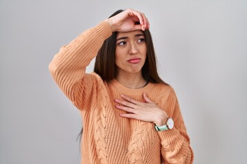 Young brunette woman standing over white background touching forehead for illness and fever, flu and cold, virus sick