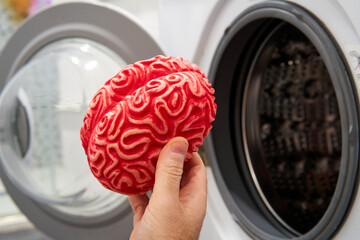 Hand Putting a Rubber Brain in a Washing Machine, Brainwashing Concept.