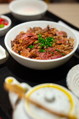 Japanese bowl of rice topped with beef steak medium rare served in restaurant.