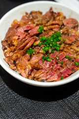 Japanese bowl of rice topped with beef steak medium rare served in restaurant.