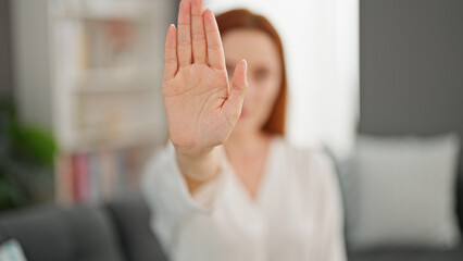 Obraz premium Young redhead woman doing stop gesture with hand at home