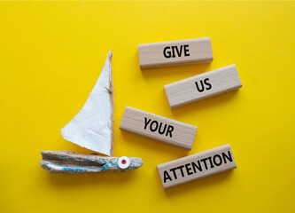 Attention symbol. Concept word Give us your attention on wooden blocks. Beautiful yellow background...