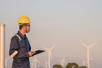 Asian Man engineers working and holding the report at wind turbine farm Power Generator Station on mountain,Thailand people,Technician man at site of work