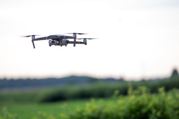 Drone flying in the sky over a green field with blurred background