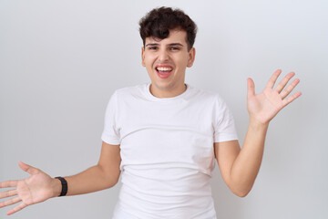 Young non binary man wearing casual white t shirt celebrating crazy and amazed for success with arms raised and open eyes screaming excited. winner concept