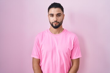 Obraz premium Hispanic young man standing over pink background relaxed with serious expression on face. simple and natural looking at the camera.