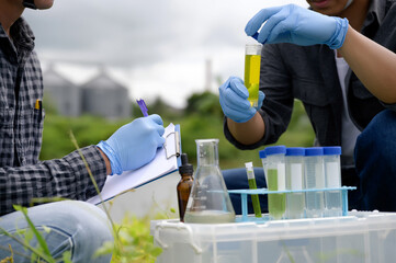 Environmental Engineers Inspect Water Quality, pH Test and Take Water sample notes in The Field Near Farmland, Fish Pond, Natural Water Sources that may be Contaminated by Suspicious Pollution Sites.